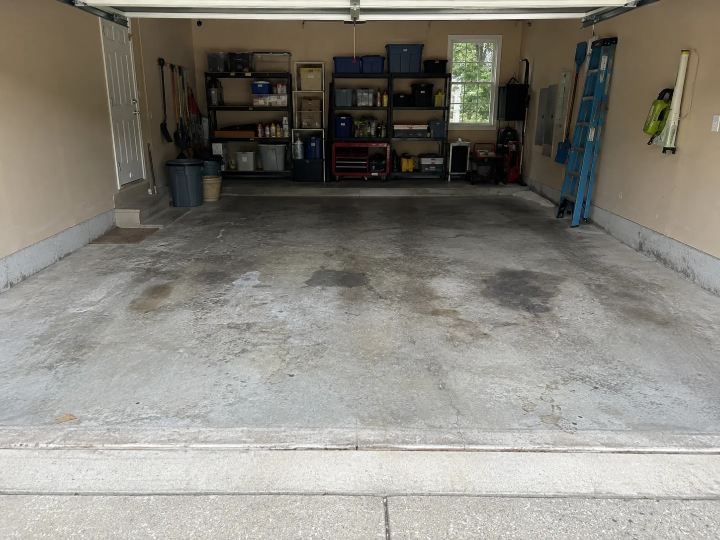 Two-car garage with worn stained bare concrete floor before coating