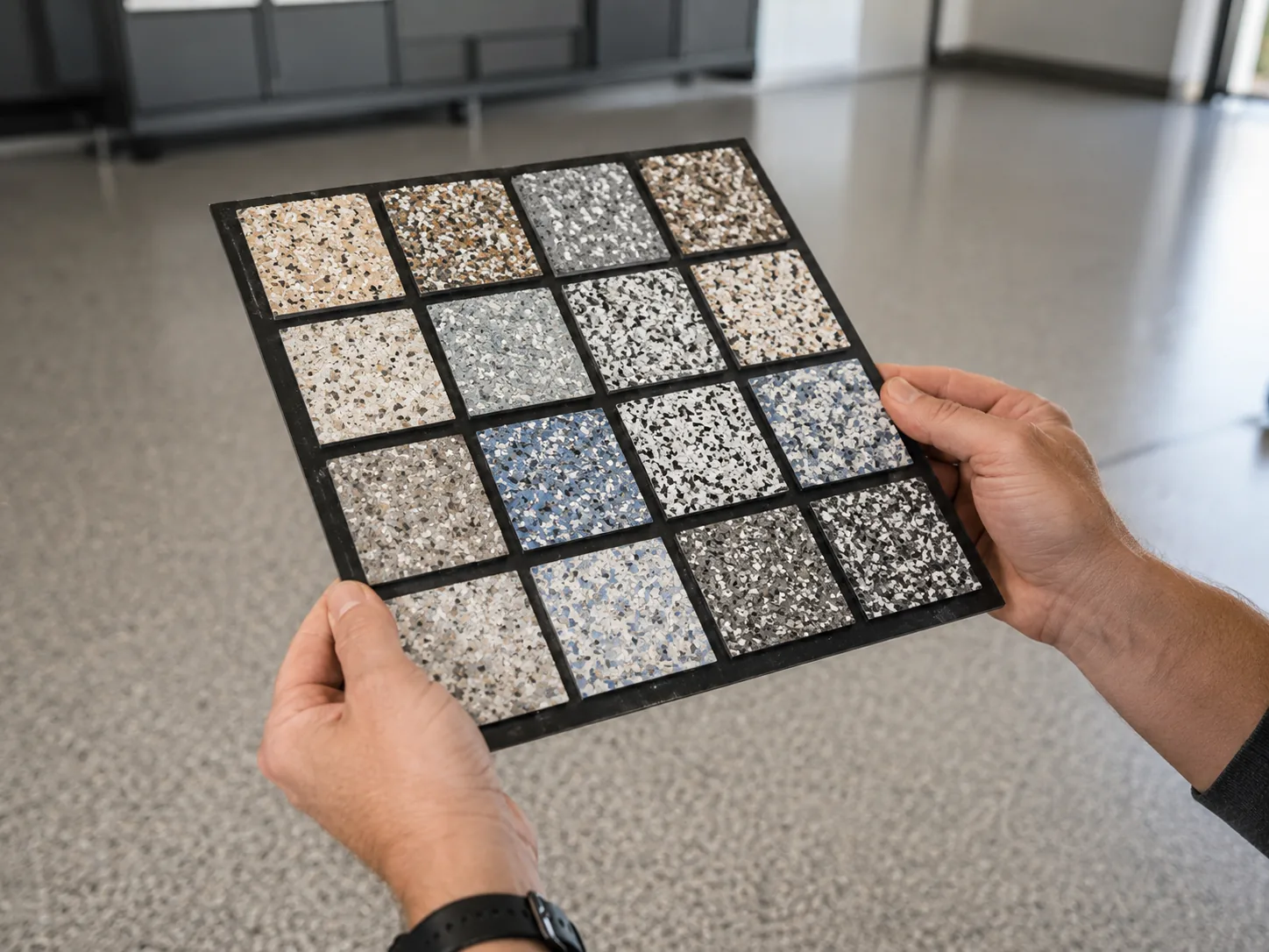 Hands holding a flake blend sample board in a garage