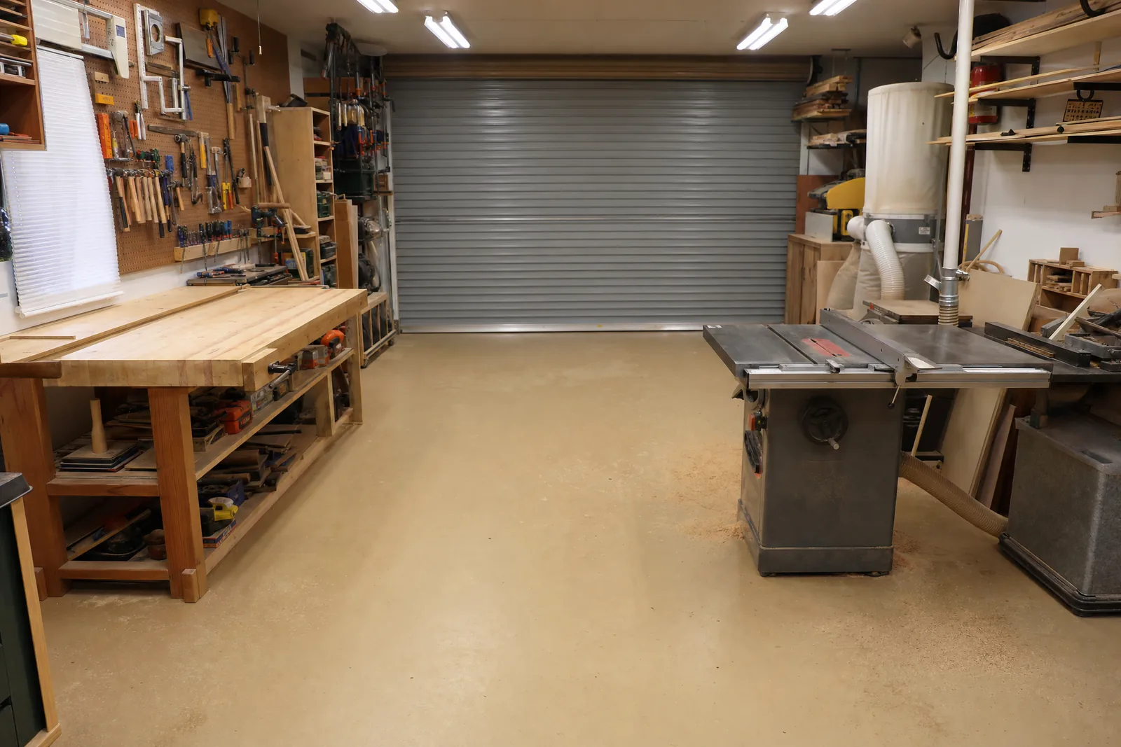 Home woodworking workshop with a solid tan epoxy floor, workbench and pegboard tool wall